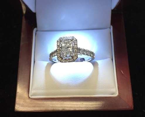 custom 1.80ct emerald radiant cut diamond surrounded by 1.42ct smaller diamonds all set in 18kt white gold