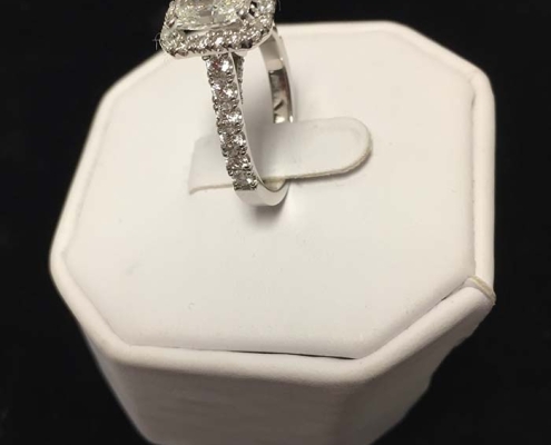 custom 1.80ct emerald radiant cut diamond surrounded by 1.42ct smaller diamonds all set in 18kt white gold