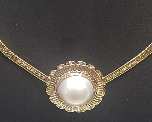 Mabé pearl is on a 14k gold chain with diamonds surrounding the pearl and extending up the chain