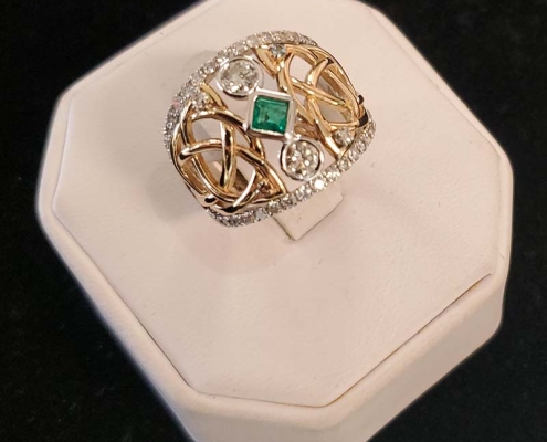 14k custom ring with Celtic design set with emerald centre with two round diamonds on each end with 1ct of diamonds surrounding centre