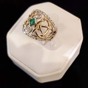 14k custom ring with Celtic design set with emerald centre with two round diamonds on each end with 1ct of diamonds surrounding centre